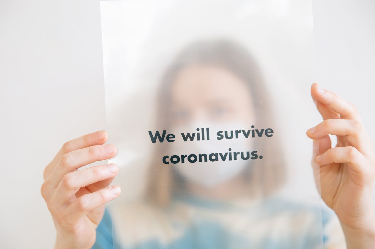 home-services-02 A person holds a sign saying We will survive coronavirus, conveying hope during the pandemic.